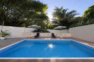 a swimming pool with two chairs and umbrellas at Flat Aeroporto - Estrada do coco - Lauro de Freitas M in Lauro de Freitas +5 photos