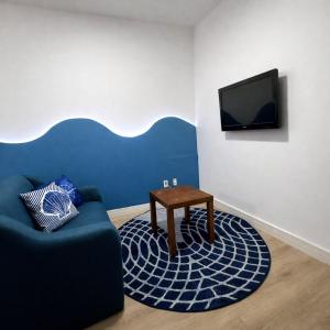 a living room with a blue couch and a table at Flat Aeroporto - Estrada do coco - Lauro de Freitas M in Lauro de Freitas