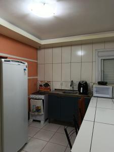 a kitchen with a refrigerator and a table in it at Casa de 1 quarto in Torres +2 photos