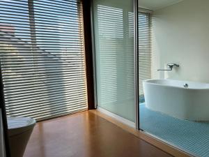 a bathroom with a tub and a toilet and a glass window at Urara Holiday in Sumoto +135 photos