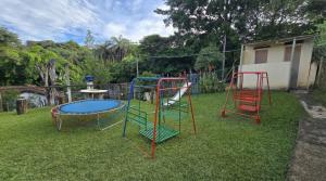 two playground equipment in a yard with a trampoline at Excelente Sitio em Juatuba in Juatuba
