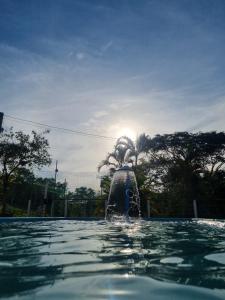 a fountain in a pool with the sun in the background at Excelente Sitio em Juatuba in Juatuba