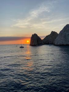 a sunset over the ocean with a boat in the water at Casa Dei Girasoli in Cabo San Lucas