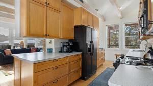 a kitchen with wooden cabinets and a black refrigerator at Mountain Treetop in Red Lodge +42 photos