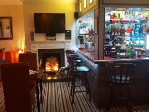 a bar in a restaurant with a fireplace and a television at Andel Lodge & Restaurant in King's Lynn