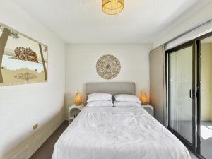 a bedroom with a large bed with white sheets at Beachside Apartment Overlooking Caseys Beach in Batehaven
