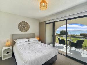 a bedroom with a bed and a view of the ocean at Beachside Apartment Overlooking Caseys Beach in Batehaven