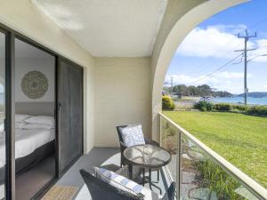 a room with a balcony with a bed and a table at Beachside Apartment Overlooking Caseys Beach in Batehaven