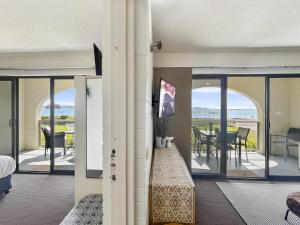 a room with a balcony with a view of the ocean at Beachside Apartment Overlooking Caseys Beach in Batehaven +20 photos