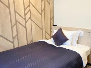 a bedroom with a bed with a blue blanket and pillows at HOTEL LiVEMAX BUDGET Chofu-Ekimae in Chofu