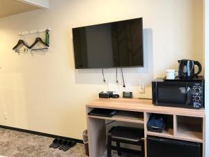 a room with a desk with a tv and a microwave at HOTEL LiVEMAX BUDGET Chofu-Ekimae in Chofu