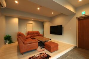 a living room with a couch and a table and a television at ゲストハウス&café chiuwo in Kawazu