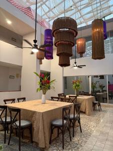 a dining room with tables and chairs and chandeliers at Hotel Mesón de la Chinantla in San Juan Bautista Tuxtepec