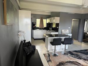 a kitchen with a counter and two stools in a room at Athaliah Stays in Suva