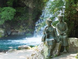 a statue of two people sitting in front of a waterfall at ゲストハウス&café chiuwo in Kawazu
