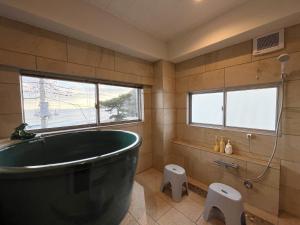 a bathroom with a large black tub and a toilet at ゲストハウス&café chiuwo in Kawazu +39 photos