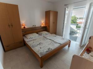 a bedroom with a bed and a large window at Apartments and rooms by the sea Palit, Rab - 5044 in Rab