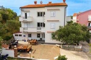 a large white building with a patio and tables at Double Room Palit 5044b in Rab