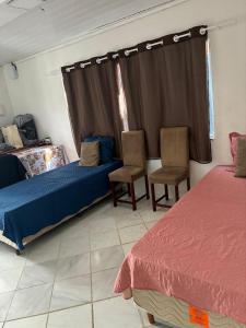 a bedroom with two beds and two chairs and a window at Casa Nossa Senhora de Nazaré 2 in Belém