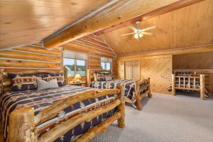 a log cabin bedroom with two beds and a ceiling fan at Spruce Lodge in Red Lodge