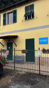 a yellow building with green shuttered windows and a fence at Affittacamere Casa Lucia in La Spezia +13 photos