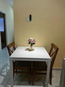 a white table with a vase of flowers on it at Homestay D'Kampong in Teluk Intan +4 photos