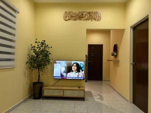 a tv in a room with a woman on a screen at Homestay D'Kampong in Teluk Intan