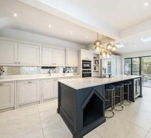 a kitchen with white cabinets and a large island with bar stools at Layla Grove in Grove Park
