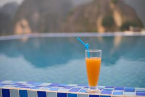 a glass of orange juice sitting next to a swimming pool at Tam Coc Sunshine Villa in Vũ Lâm