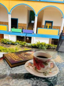 Eine Tasse Kaffee steht mit einem Buch auf einem Tisch. in der Unterkunft Hostal Capullode Seda in Zapatoca