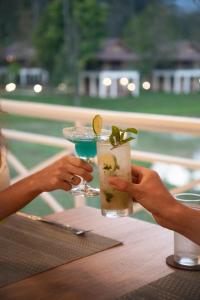 two people holding a drink on a table at Lost Horizon Resort - Khao Sok in Khao Sok National Park +32 photos
