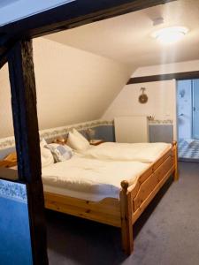 a bedroom with a wooden bed with white sheets at Alte Weinstuben Steinfelder Hof - B&B in Ellenz-Poltersdorf