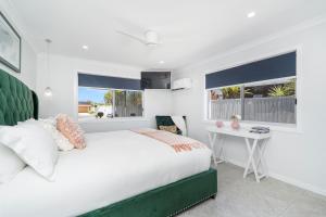 a bedroom with a bed and a desk and two windows at Pet Friendly Beach House with pool - Sleeps 10 in Urangan +28 photos