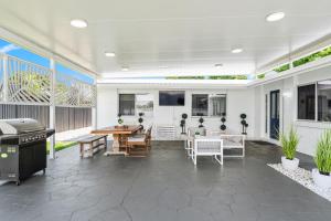 a patio with a grill and a table and chairs at Pet Friendly Beach House with pool - Sleeps 10 in Urangan