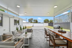 a patio with a table and chairs and a grill at Pet Friendly Beach House with pool - Sleeps 10 in Urangan