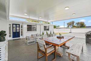 a patio with a wooden table and chairs and a grill at Pet Friendly Beach House with pool - Sleeps 10 in Urangan