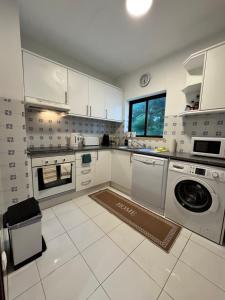 a kitchen with white cabinets and a washer and dryer at Casa Julio-Rooftop Terrace & Pool 5 Min to Beach in Carvoeiro