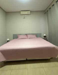 a bedroom with a large bed with pink pillows at Casa Lagoa Maior Espaçosa e confortável! in Três Lagoas