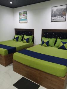 two beds in a room with green and blue at Moonlight Resort in Anuradhapura +14 photos