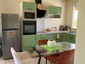 a kitchen with green cabinets and a glass table with chairs at La villa Surette in Capesterre