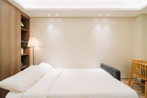 a bedroom with a white bed and a chair at Dragon's Keep BNB near NAIA and MOA in Manila