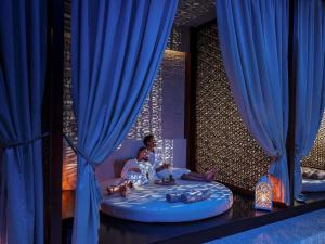 a woman and child sitting in a bed with blue curtains at Rixos Borovoe in Borovoye +216 photos
