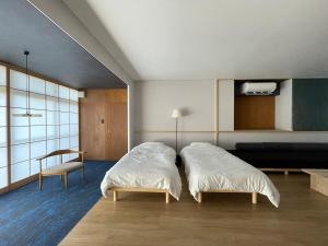 a bedroom with two beds and a chair in it at 古街のアトリエ in Utazu +51 photos