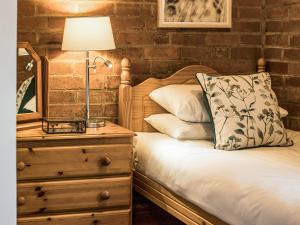 a bedroom with a bed with a lamp on a dresser at Yarlington Mill in Ledbury