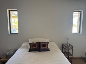 a white bed with two windows in a bedroom at Refugio del Indalo in Termas de Guaviyú