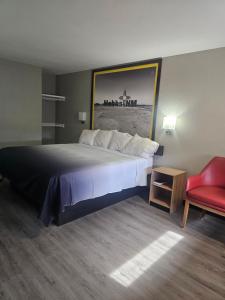 a large bed in a hotel room with a red chair at Super 8 by Wyndham Hobbs in Hobbs +7 photos