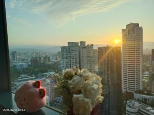 a vase of flowers on a window sill with a city at Niwill Homestay in Taichung