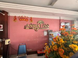 an animal inn sign on a pink wall with flowers at Anika Inn Kluang in Kluang