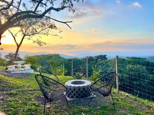 two chairs and a table in a field with the sunset at Villa Sura in Colón