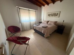 a bedroom with a bed and two red chairs at Doña Mercedes in Verónica